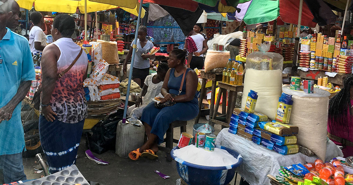 A woman sits behind a stall in a busy market