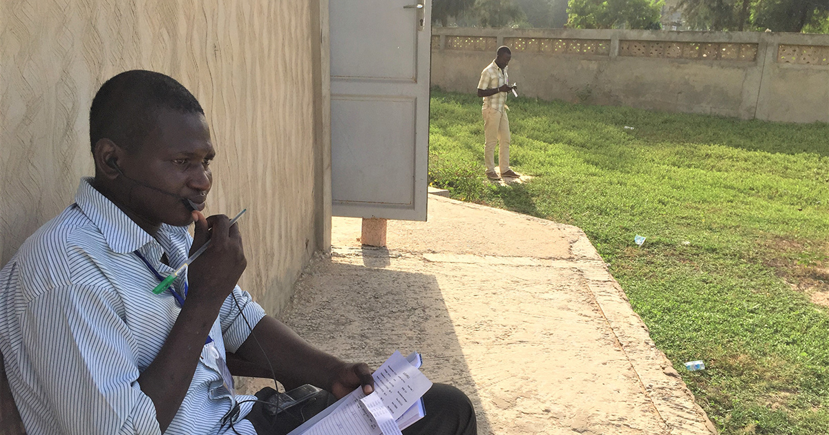 A telephone interviewer in Senegal finds a quiet outdoor space for surveying.