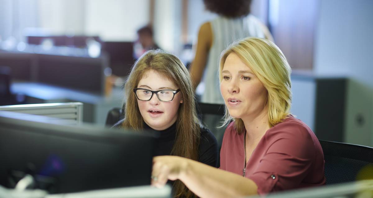 Two women looking at a monitor in a cubicle