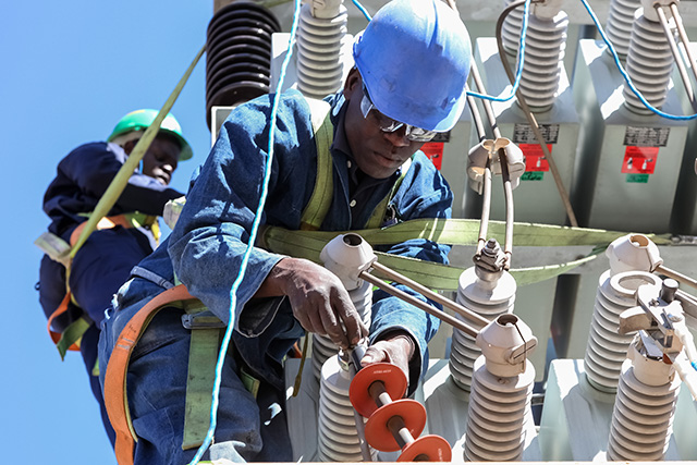 Electricians in Africa working on high voltage power lines