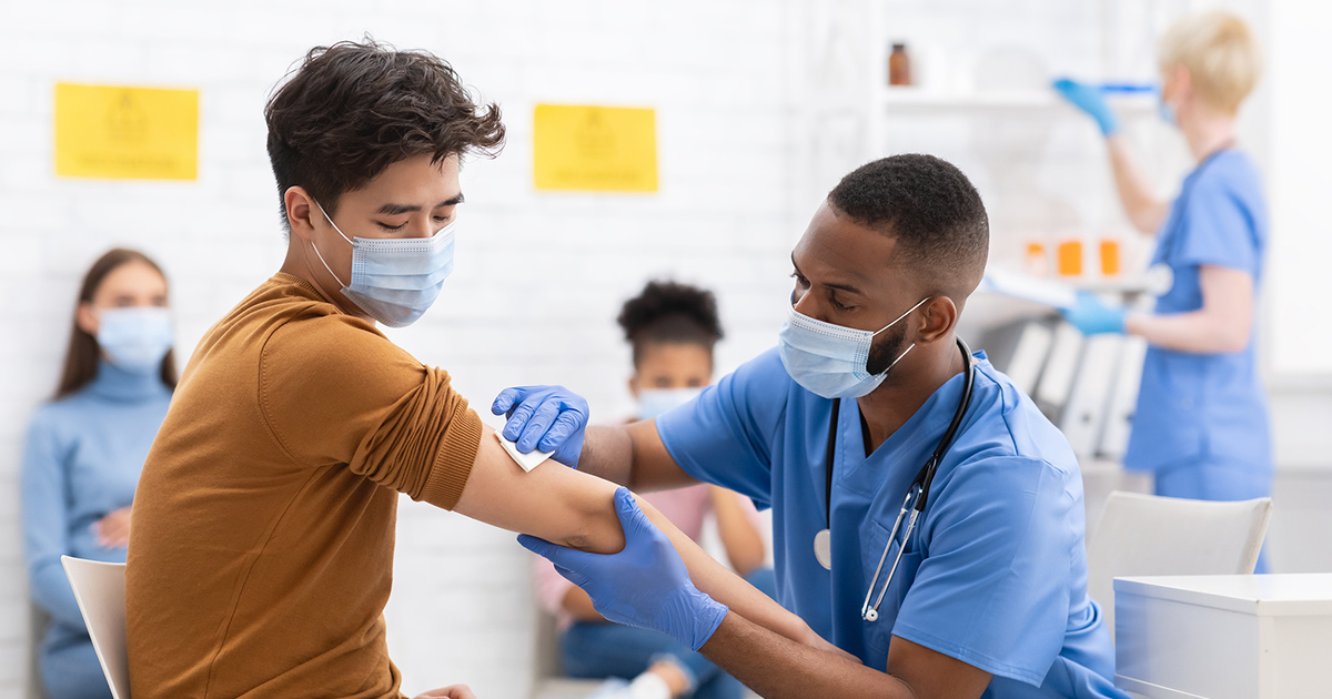 Covid-19 Vaccination. Asian Male Patient Getting Vaccinated Against Coronavirus Receiving Covid Vaccine Intramuscular Injection During Doctor's Appointment In Hospital. Corona Virus Immunization