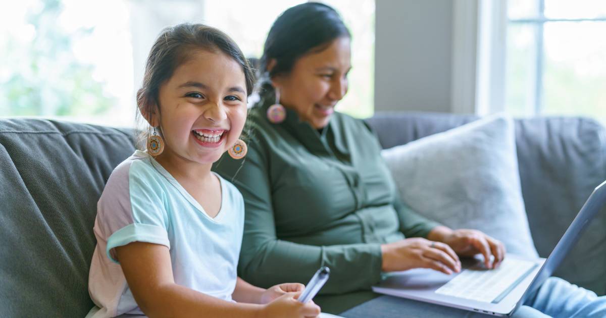 American Native mother and daughter sitting on the couch doing homework