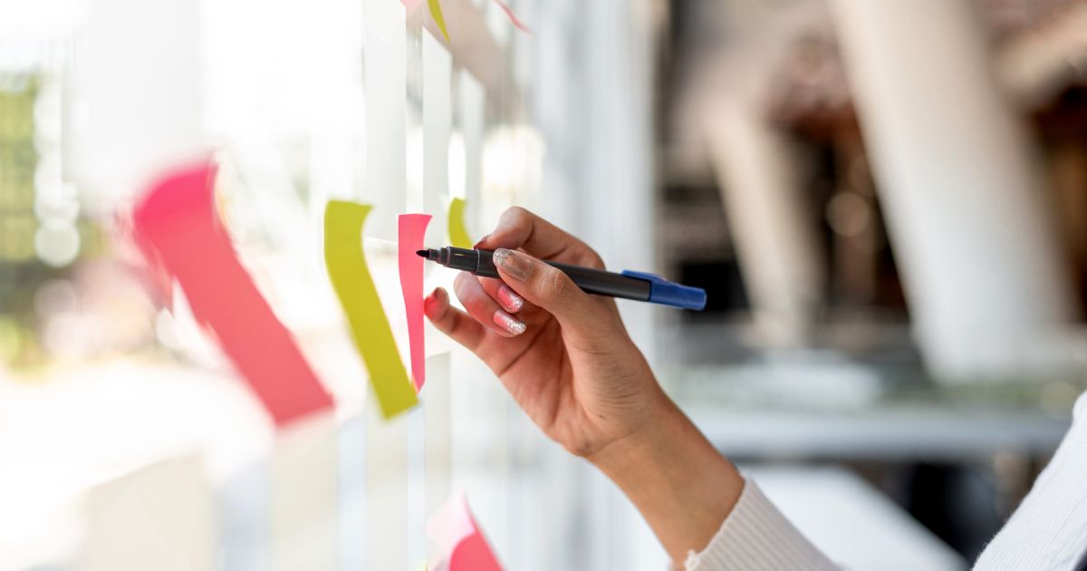 Young Businesswoman Creating Project Plan on Office Wall with Paper Notes
