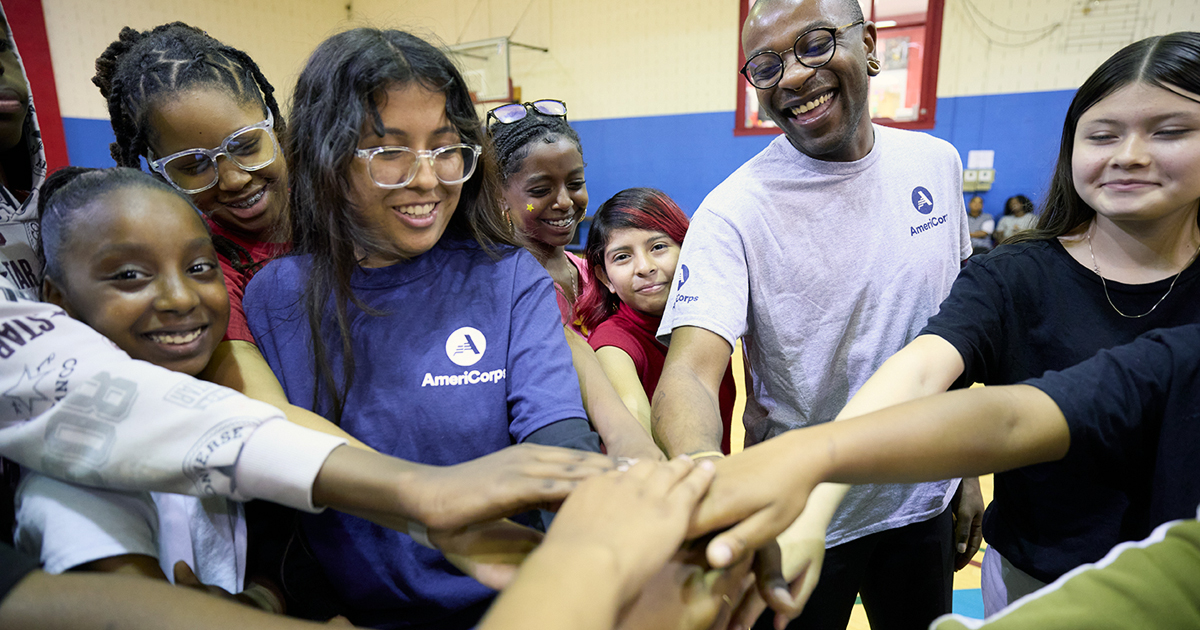 A group of smiling AmeriCorps team members in a huddle. 