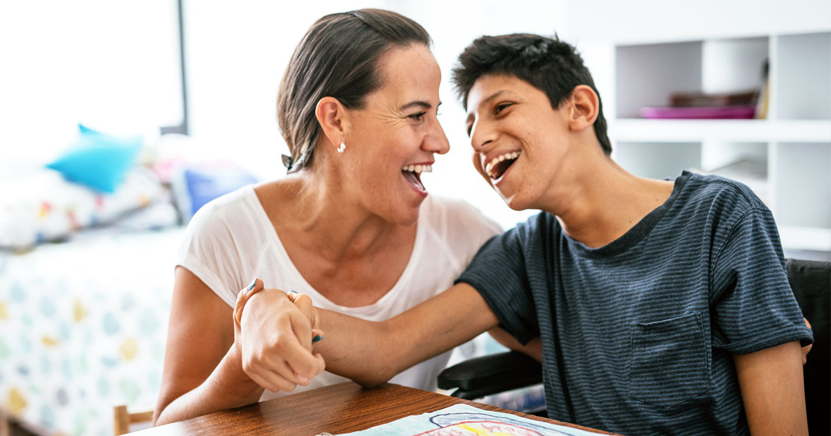 Disabled Latino teenager with Celebral Palsy and mother laughing