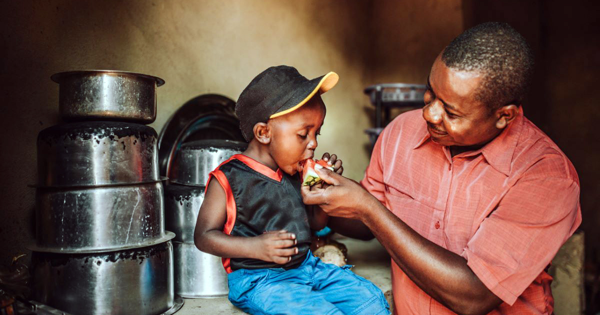 A father feeding his young child watermelon